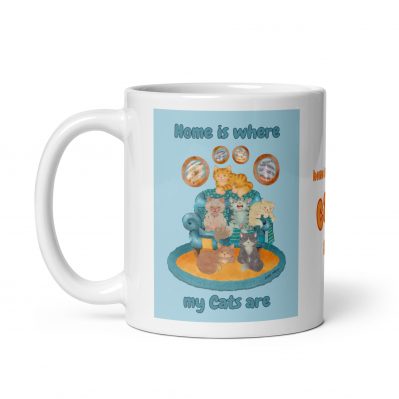 Ceramic mug featuring illustration of sleeping cats on an armchair with framed portraits of rescue cats on the wall, titled "Home is Where My Cats Are"